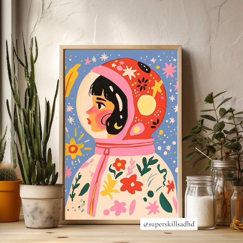 May include: A colorful illustration of a person wearing a pink and red astronaut helmet with a white spacesuit decorated with flowers and stars. The background is a blue sky with white stars. The text "@superskillsaddhd" is at the bottom of the image.