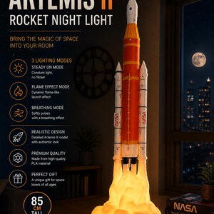 May include: An Artemis II rocket night light standing 85 cm tall. The model features a white and orange rocket body with NASA branding, illuminated by a glowing, textured orange base that mimics a launch flame. Text includes Artemis II.
