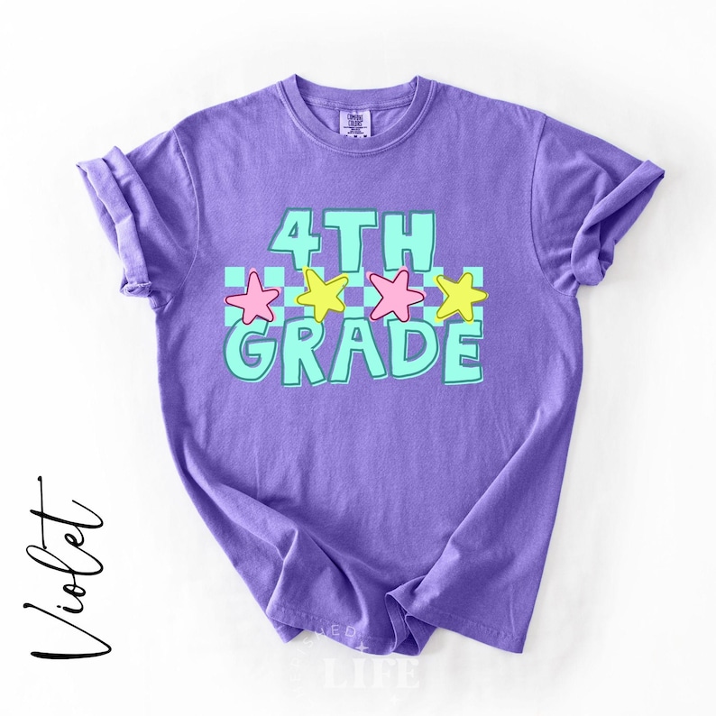 May include: Violet-colored t-shirt with the text "4TH GRADE" in turquoise, outlined in white. The design includes pink and yellow stars. The shirt is a comfortable, casual style.