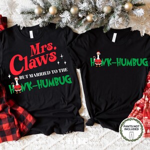 May include: Two black t-shirts with Christmas-themed text. One reads "Mrs. Claws" in red, with "BUT MARRIED TO THE HONK-HUMBUG" in green. The other says "HONK-HUMBUG" in green. Both shirts feature a goose wearing a Santa hat.