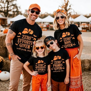 May include: Four black t-shirts with orange graphics of ghosts, bats, and stars. The shirts feature the text: Zero Efforts Given, Zero Boos Given, Zero Apologies Given, and Zero Pranks Given, each including the text smith family, 2026.