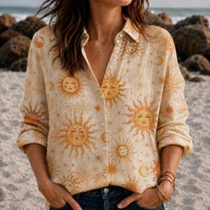 May include: A long-sleeved button-down shirt in a light beige color featuring an all-over print of golden yellow suns, crescent moons, and small starbursts. The shirt has a classic collar, a front button placket, and cuffed long sleeves.