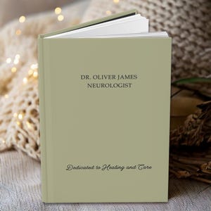 K&ouml;nnte beinhalten: Ein gr&uuml;nes Buch mit dem Text "DR. OLIVER JAMES NEUROLOGIST" und "Dedicated to Healing and Care" auf dem Einband.