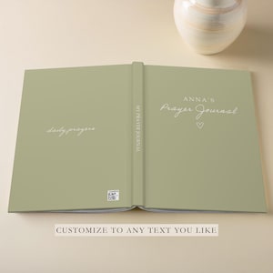 K&ouml;nnte beinhalten: Ein gr&uuml;nes Gebetsbuch mit dem Text "ANNA'S Prayer Journal" auf dem vorderen Umschlag und "daily prayers" auf dem hinteren Umschlag.