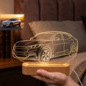 May include: A glowing car-shaped LED night light. The light is a detailed outline of a car, emitting a warm white glow. It sits on a rectangular wooden base. A small picture of a car is in the background.