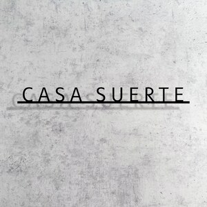 May include: A white wall with the words "CASA SUERTE" written in black lettering.