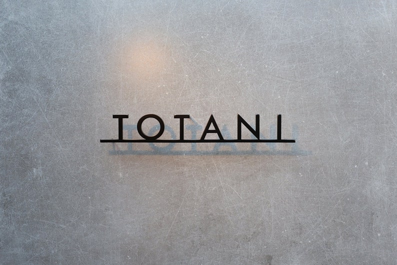 Puede incluir: Primer plano de una puerta de vidrio esmerilado con la palabra "TOTANII" escrita en letras negras.