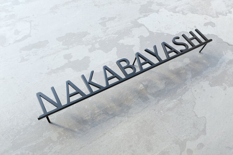 May include: Black metal sign with the name "NAKABAYASHI" in all caps.