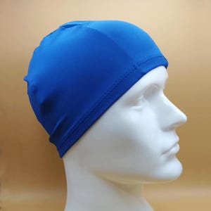 May include: A vibrant blue swim cap made of a smooth, stretchy material. The cap is designed to fit snugly and cover the head, often used for swimming to reduce drag and protect hair from chlorine.