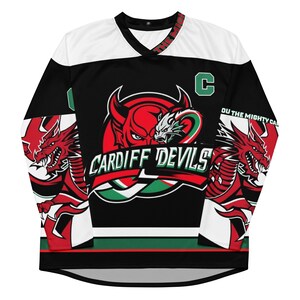 May include: Black and white hockey jersey with a red dragon and devil graphic. The jersey has the text "CARDIFF DEVILS" and "YOU THE MIGHTY CARDIFF DEVILS" on it.