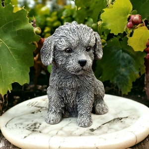 May include: A gray, furry, poodle-like dog figurine sitting on a white, round, decorative plate.