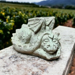 May include: A sleeping green dragon garden statue with closed eyes and a detailed face. The statue is made of concrete and has a textured surface.
