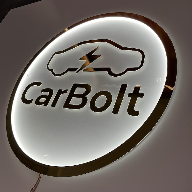 May include: A round, illuminated sign with a gold-colored trim. The sign features a car silhouette with a lightning bolt and the text "CarBolt" in a bold font. The background is white with a bright, glowing effect.