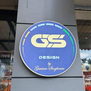 May include: A blue and yellow circular sign with the letters "GS" in white, surrounded by a white and green ring. The text "DESIGN by Gautam Singhania" is below the letters.