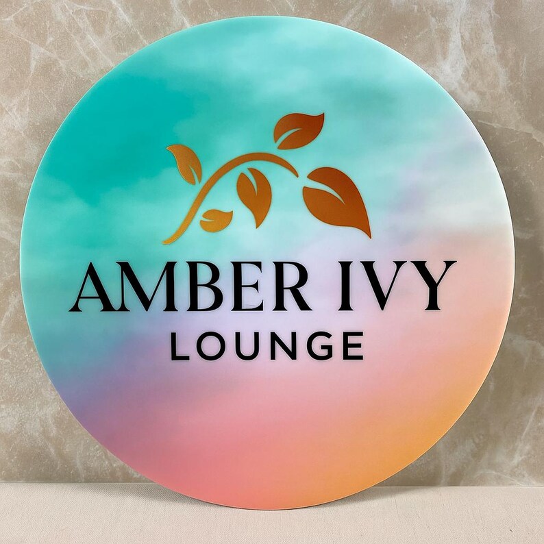 May include: A round sign with a gradient background of teal, purple, and orange. The sign features the text "AMBER IVY LOUNGE" in black, with a gold-colored leaf design above the text.