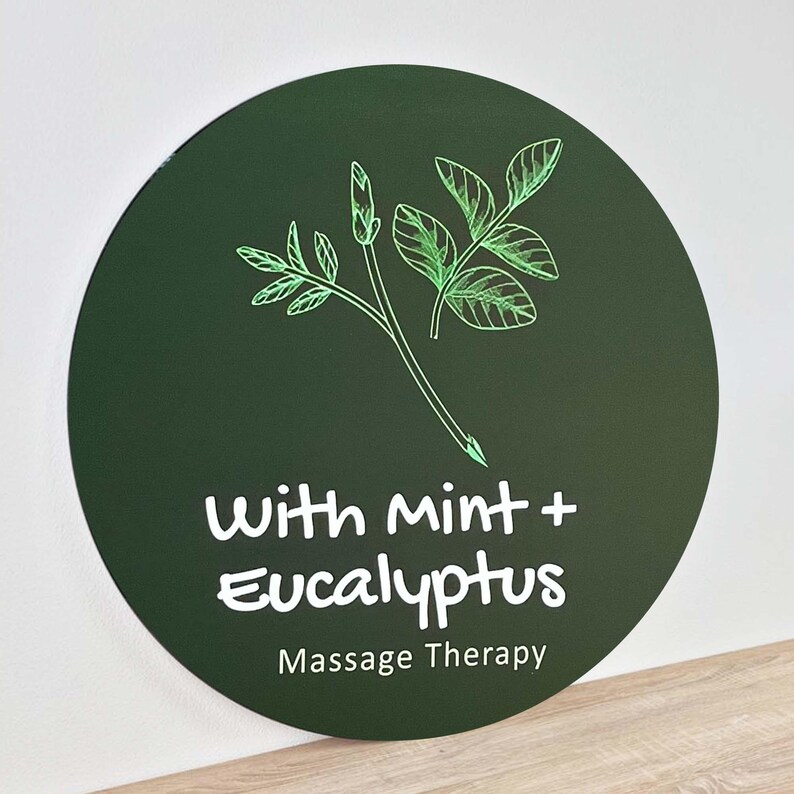 May include: A green circle with a white outline and the text "With mint + Eucalyptus" and "Massage Therapy" in white. A green line drawing of a sprig of mint and eucalyptus leaves is above the text.