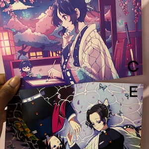 May include: Two anime art prints. One features a woman with a butterfly hair accessory against a night sky with a crescent moon. The other shows two characters with butterflies. The prints have a Japanese anime style.