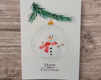 Tarjeta navideña en acuarela – Ilustración de adorno navideño con muñeco de nieve | Tarjeta festiva hecha a mano | Tarjeta de felicitación invernal en acuarela