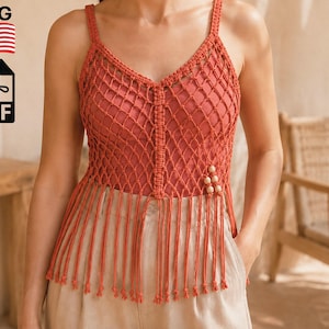 May include: A rust-colored macrame tank top featuring a V-neckline, a diamond-shaped knotted net pattern, thin shoulder straps, and a long fringe hem. The garment is accented with small, light-colored wooden beads on the lower right side.