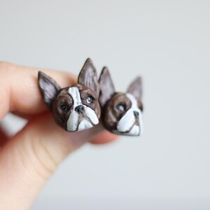 Puede incluir: Un par de pendientes de bulldog francés hechos de arcilla polimérica, de color marrón y blanco.