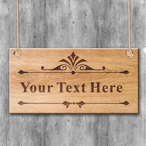May include: A wooden sign with a decorative design and the text "Your Text Here" hanging from two ropes against a concrete wall.