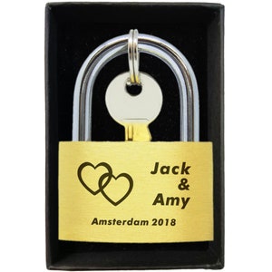 May include: Gold padlock with a key, engraved with the names Jack & Amy, and the date Amsterdam 2018. Two intertwined hearts are above the names.