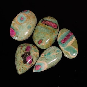 Könnte beinhalten: Fünf grüne und rosafarbene Edelsteine ​​in Cabochon-Schliff in verschiedenen Formen und Größen. Die Steine ​​haben eine marmorierte grün-rosa Farbe mit einem glänzenden Finish.