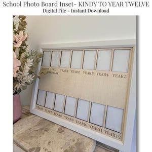 May include: A white framed school photo board with spaces for photos from Kindy to Year 12. The board has a light wood-colored center with text that reads "School Photo Board Inset - KINDY TO YEAR TWELVE" and "Digital File - Instant Download".