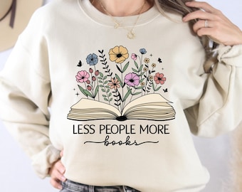 May include: A cream-coloured sweatshirt with a graphic of an open book with flowers growing out of it. The text "Less People More Books" is printed below the book.