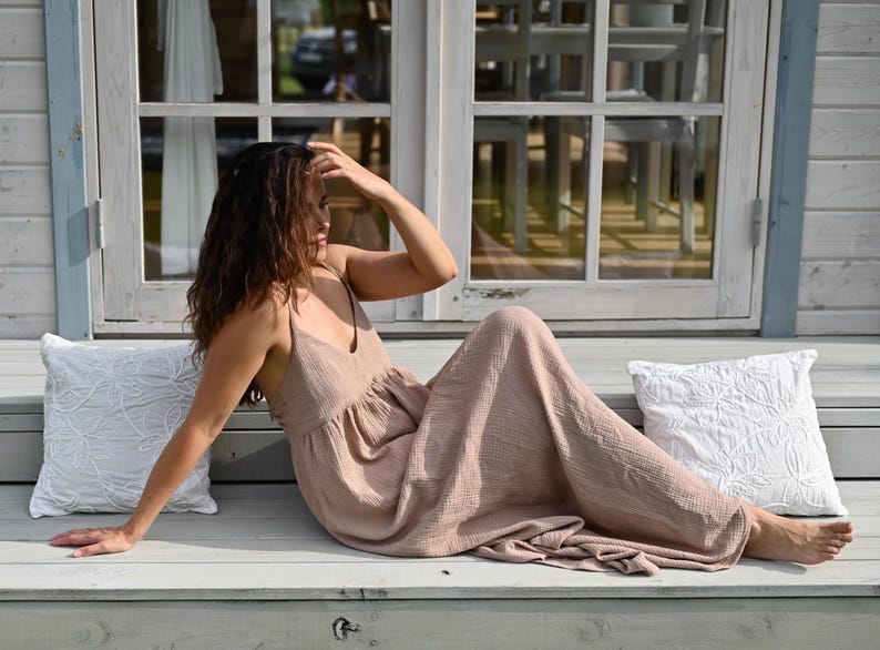 Taupe backless cotton maxi dress with deep V-neckline and open tie back. Made from breathable double gauze muslin, Oeko-Tex certified. Flowy A-line silhouette, perfect for boho bridesmaids, Greek goddess looks, and summer weddings. A lightweight gauze sun dress that’s handmade, easy to pack, and elegant for barefoot moments and garden gatherings.