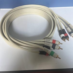 Könnte beinhalten: Ein Satz von vier weißen RCA-Kabeln mit vergoldeten Steckern. Die Kabel sind zusammengerollt und die Stecker sind sichtbar.