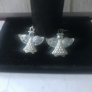 May include: A pair of silver angel earrings with blue crystal accents.