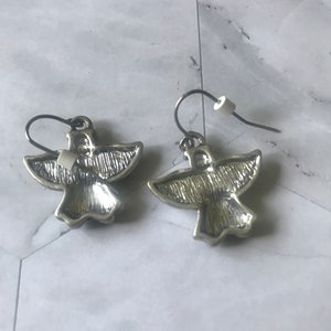 May include: A pair of silver angel wing earrings with a textured finish.