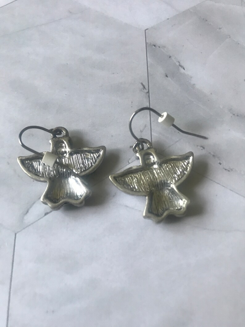 May include: A pair of silver angel wing earrings with a textured finish.