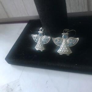 May include: A pair of silver angel earrings with blue crystal accents.