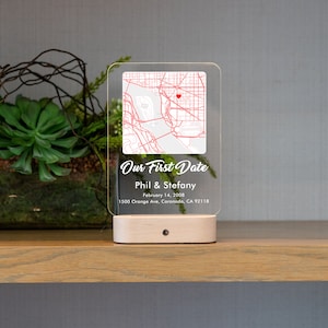 May include: A clear acrylic light-up sign with a map of a city and a red heart marking a location. The sign reads "Our First Date", "Phil & Stefany", "February 14, 2008", and "1500 Orange Ave, Coronado, CA 92118".