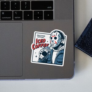 SVGPNG illustration of the famous horror character drinking iced coffee through his mask, labeled with the text Emotional Support Iced Coffee. This Quirky and humorous design blends the iconic Halloween horror with coffee culture