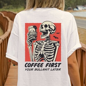 SVG PNG illustration of a skeleton holding a coffee cup with the humorous text Coffee first, Your bullshit later, designed in a playful style to celebrate Halloween. This quirky design combines a love for coffee with a cheeky message.