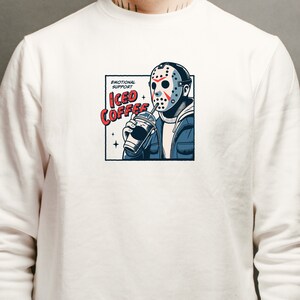 SVGPNG illustration of the famous horror character drinking iced coffee through his mask, labeled with the text Emotional Support Iced Coffee. This Quirky and humorous design blends the iconic Halloween horror with coffee culture