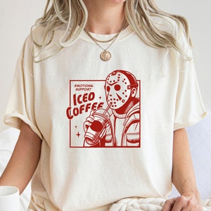 SVGPNG illustration of the famous horror character drinking iced coffee through his mask, labeled with the text Emotional Support Iced Coffee. This Quirky and humorous design blends the iconic Halloween horror with coffee culture