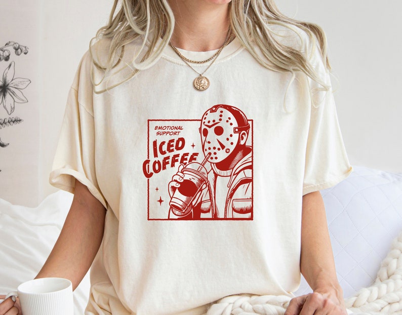 SVGPNG illustration of the famous horror character drinking iced coffee through his mask, labeled with the text Emotional Support Iced Coffee. This Quirky and humorous design blends the iconic Halloween horror with coffee culture