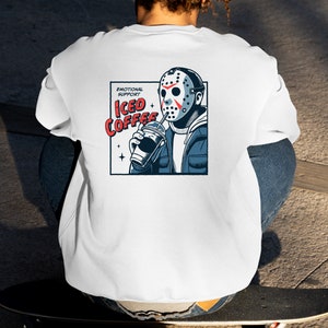 SVGPNG illustration of the famous horror character drinking iced coffee through his mask, labeled with the text Emotional Support Iced Coffee. This Quirky and humorous design blends the iconic Halloween horror with coffee culture