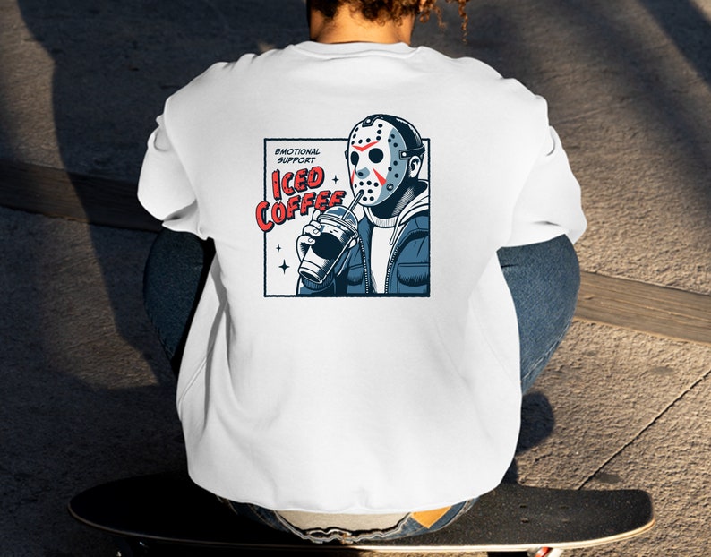SVGPNG illustration of the famous horror character drinking iced coffee through his mask, labeled with the text Emotional Support Iced Coffee. This Quirky and humorous design blends the iconic Halloween horror with coffee culture