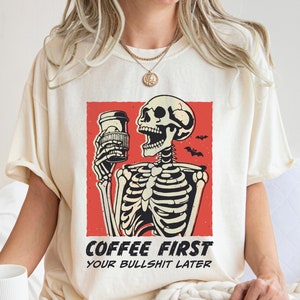 SVG PNG illustration of a skeleton holding a coffee cup with the humorous text Coffee first, Your bullshit later, designed in a playful style to celebrate Halloween. This quirky design combines a love for coffee with a cheeky message.