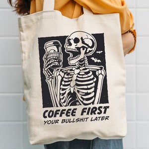 SVG PNG illustration of a skeleton holding a coffee cup with the humorous text Coffee first, Your bullshit later, designed in a playful style to celebrate Halloween. This quirky design combines a love for coffee with a cheeky message.