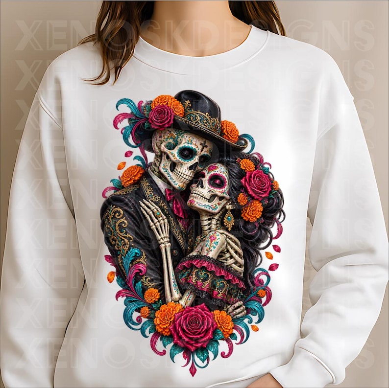 May include: A white long-sleeve sweatshirt featuring a central graphic of two skeletons embracing. The skeletons are adorned with colourful floral patterns, wearing a black hat and dark clothing, surrounded by vibrant orange and pink roses.