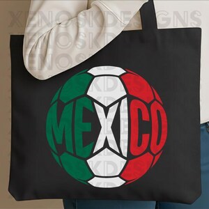 May include: A black tote bag featuring a graphic of a soccer ball designed with the colors of the Mexican flag, green, white, and red. The word MEXICO is printed in large, bold, black capital letters across the center of the soccer ball graphic.