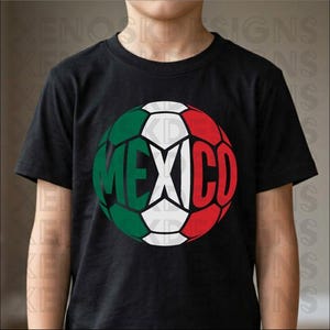 May include: A black short-sleeved t-shirt featuring a large graphic of a soccer ball on the chest. The ball is colored with the green, white, and red stripes of the Mexican flag and has the word MEXICO printed in bold black letters across the center.