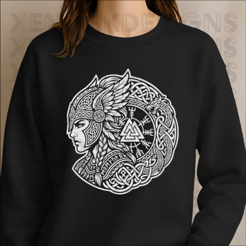 Op de afbeelding: Zwarte sweatshirt met een witte afbeelding van een Viking-krijger in profiel, versierd met een gevleugelde helm en ingewikkeld knoopwerk. Het ontwerp bevat een cirkelvormig embleem met runen en een driehoekig symbool, dat een gedetailleerde, artistieke stijl laat zien.