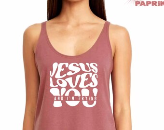 May include: A mauve tank top with a white graphic that says "Jesus Loves You and I'm Trying".